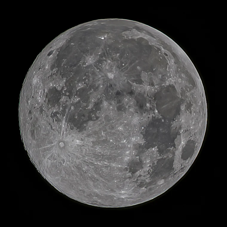 A full moon against a black sky, its craters and rays sharp